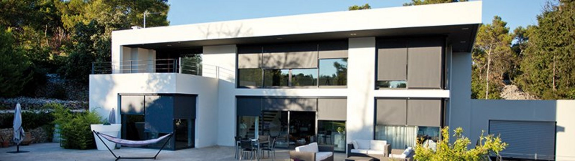 weißes Haus mit vielen Fenstern mit einem Pool und Liegestühlen im Vordergrund