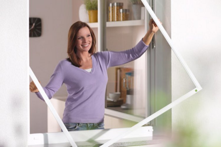 lächelnde Frau hält Insektenschutzgitter