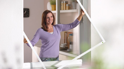 lächelnde Frau hält Insektenschutzgitter